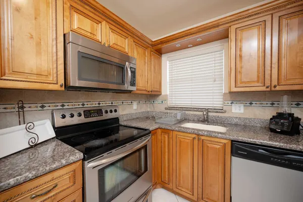 a kitchen with granite countertop a stove sink and cabinets