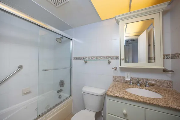 a bathroom with a granite countertop sink toilet and shower