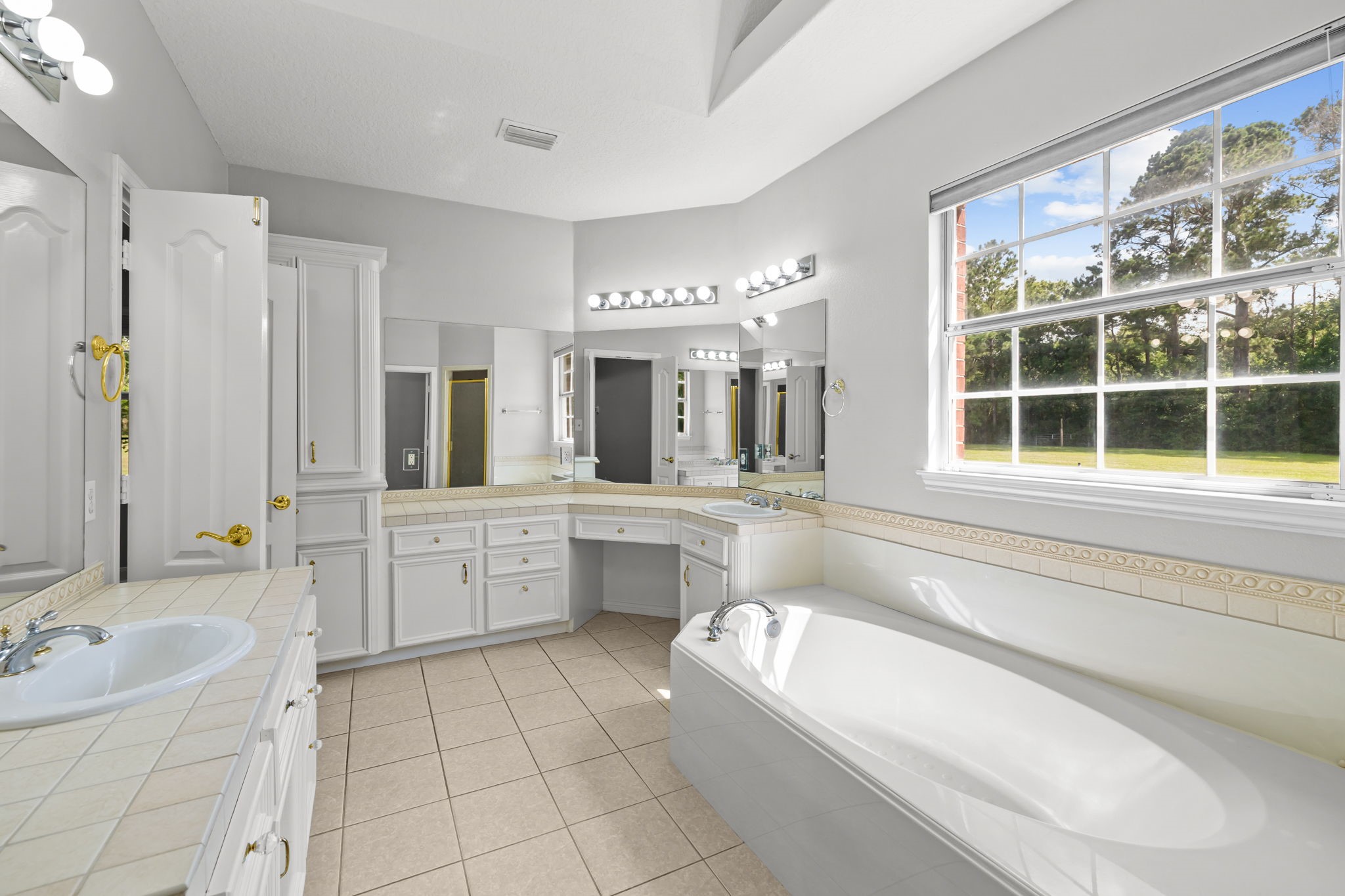 6410 Old Chocolate Bayou Road Manvel, TX 77578 - Photo 19 of 49 This bright bathroom features a
large window with a view,
spacious countertops with dual
sinks, ample cabinetry, a
luxurious soaking tub, and a
separate shower, providing both
functionality and comfort.