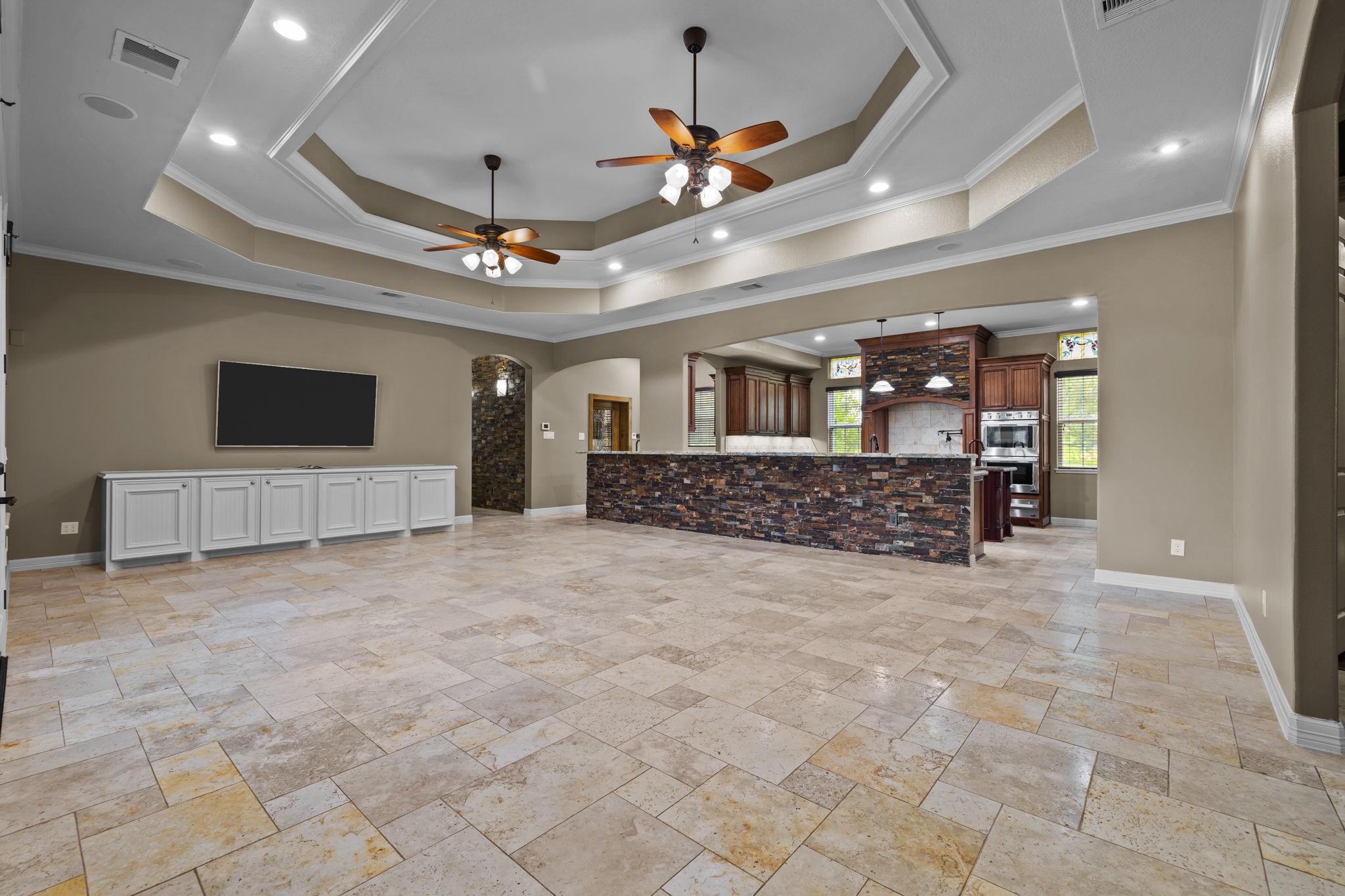 6410 Old Chocolate Bayou Road Manvel, TX 77578 - Photo 32 of 49 Expansive open living area anchored by a stone-accented chef’s kitchen and full wall of built-ins, designed for effortless indoor-outdoor entertaining with French doors leading to the covered patio, outdoor kitchen, and pool/spa.