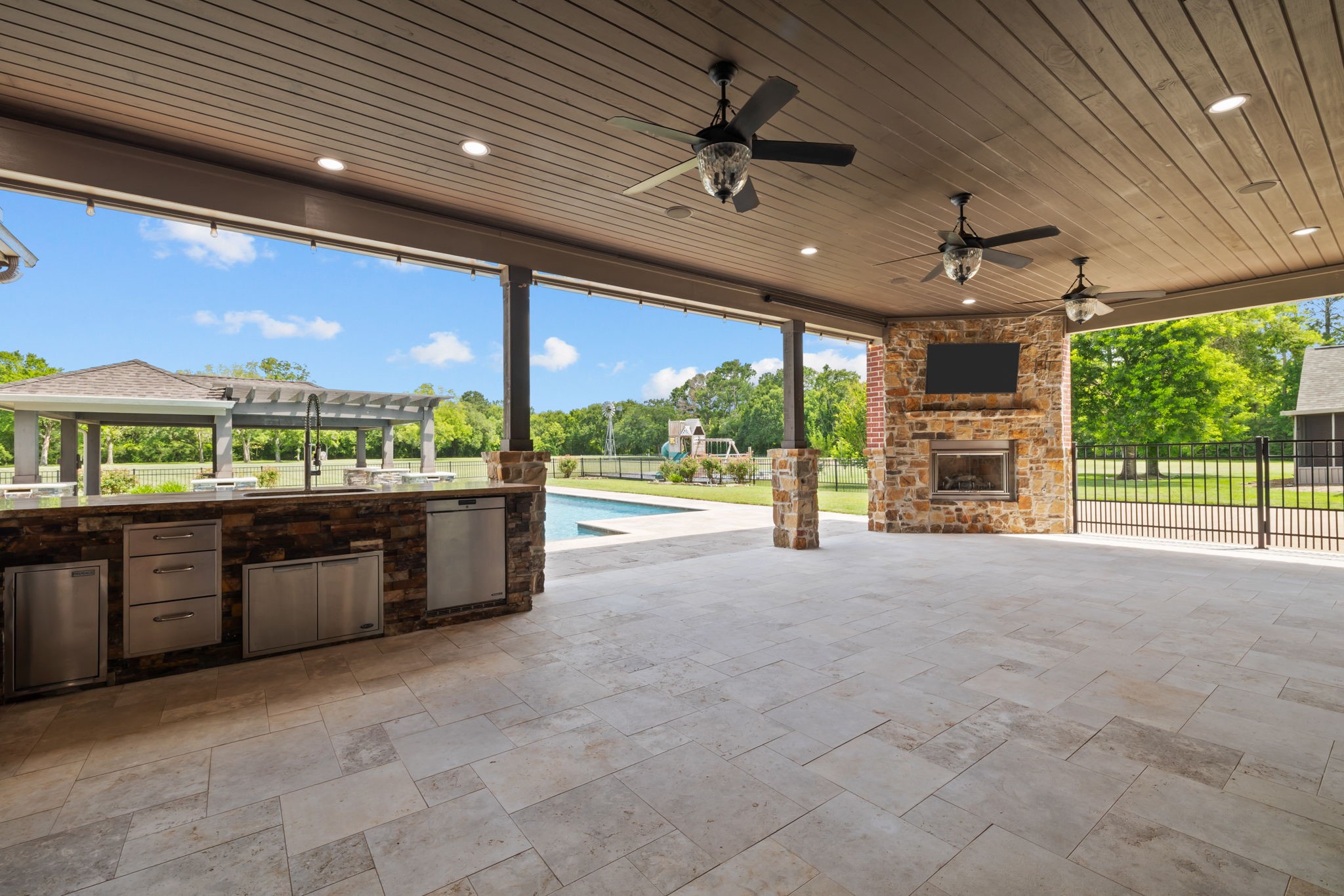6410 Old Chocolate Bayou Road Manvel, TX 77578 - Photo 44 of 49 Resort-style covered outdoor living area complete with full kitchen, beverage coolers, fireplace with mounted TV, and panoramic views of the pool and property beyond.