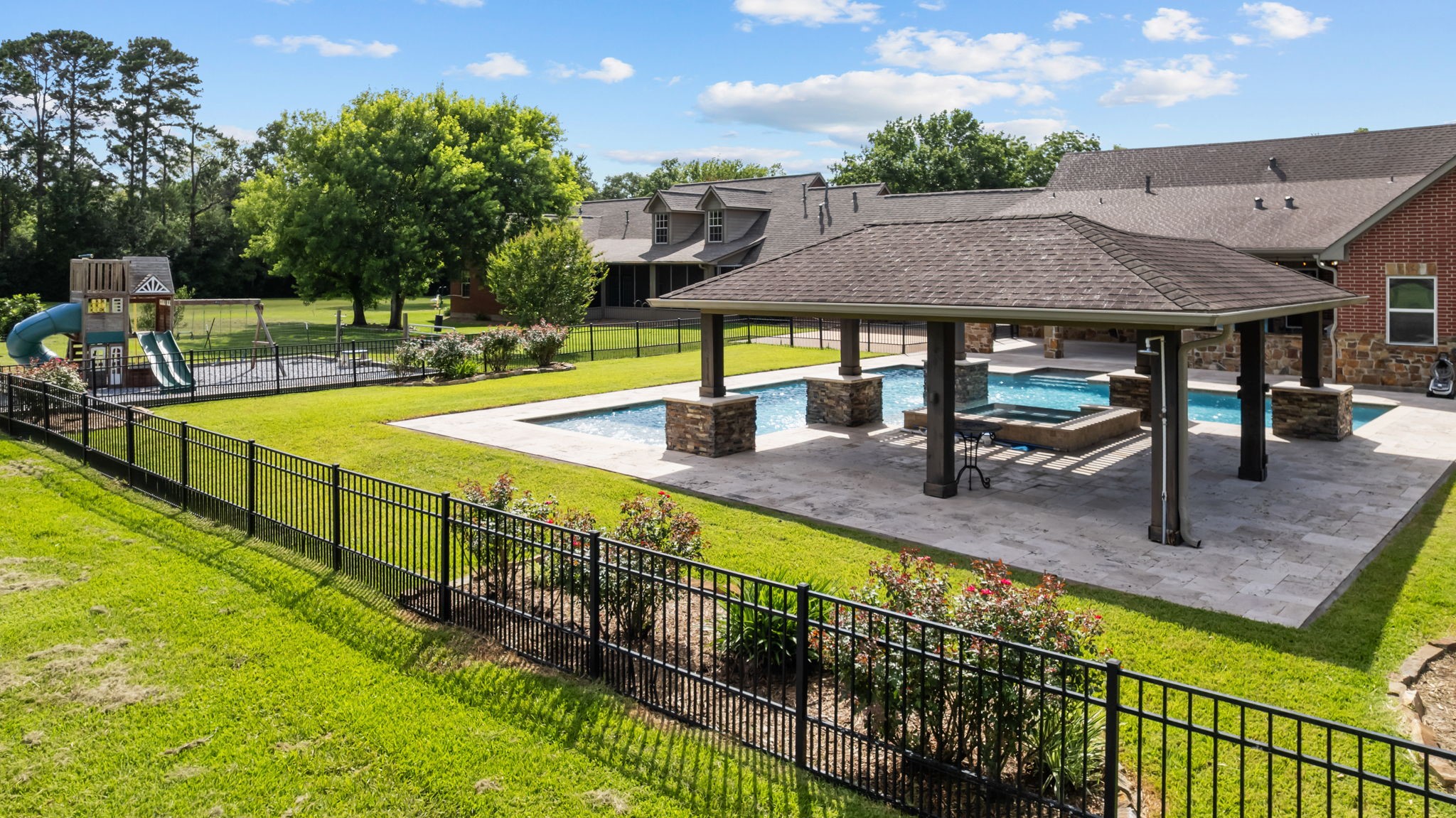 6410 Old Chocolate Bayou Road Manvel, TX 77578 - Photo 48 of 49 This property features a
spacious backyard with a
swimming pool, covered patio,
and play area with a slide and
swings, all surrounded by a well-maintained lawn and garden with Texas native plants.