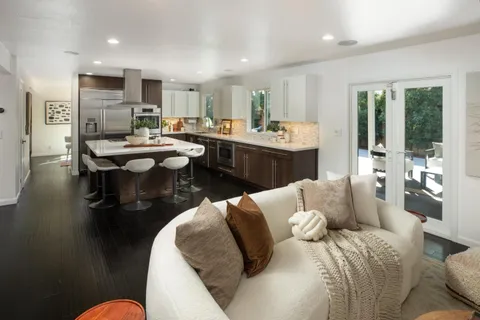 a living room with furniture kitchen view and a large window