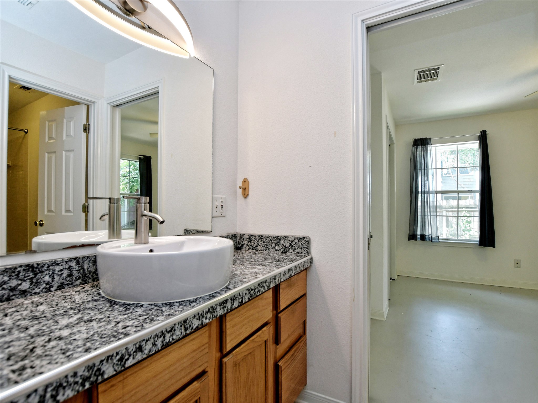 4604 Red River Street, Unit A Austin, TX 78751 - Photo 12 of 15 Vanity featuring a vessel sink, granite-style countertop, and wood-finish cabinetry