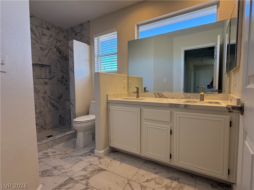 1908 Thunder Ridge Circle Henderson, NV 89012 - Photo 25 of 28 Marble-inspired tiling and a dual vanity with a large mirror enhance this bathroom's clean aesthetic.