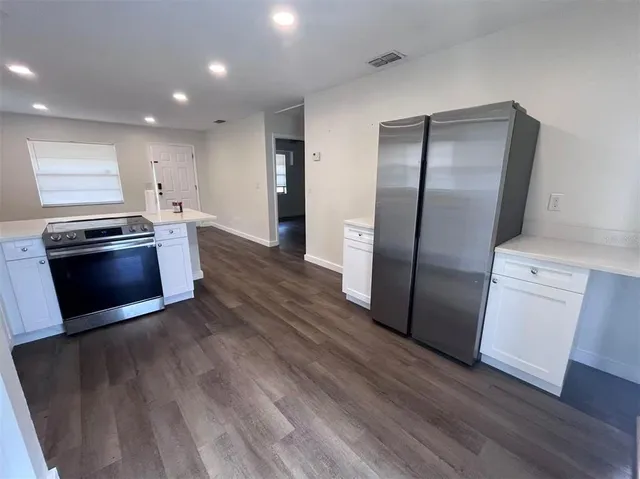 a kitchen with stainless steel appliances granite countertop a refrigerator a sink a stove and wooden floor