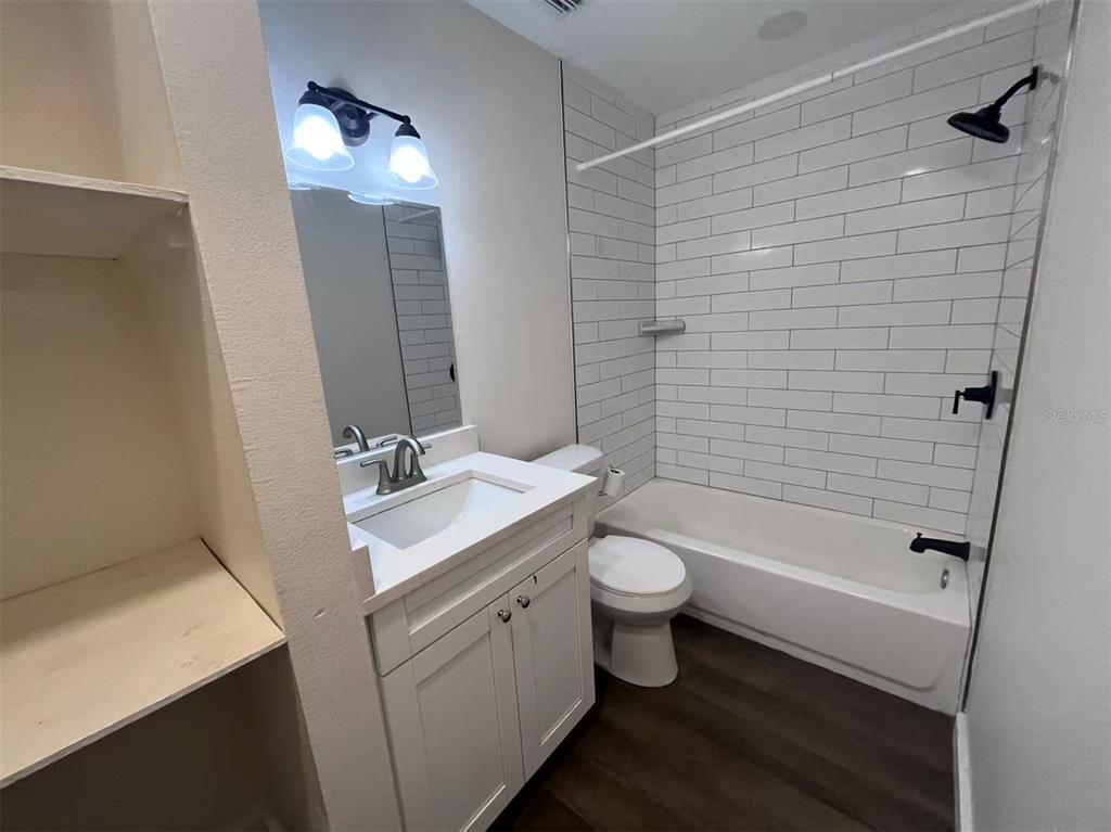 1016 9th Avenue Northwest, Unit B Largo, FL 33770 - Photo 7 of 11 a bathroom with a granite countertop toilet a sink a mirror a bathtub and shower
