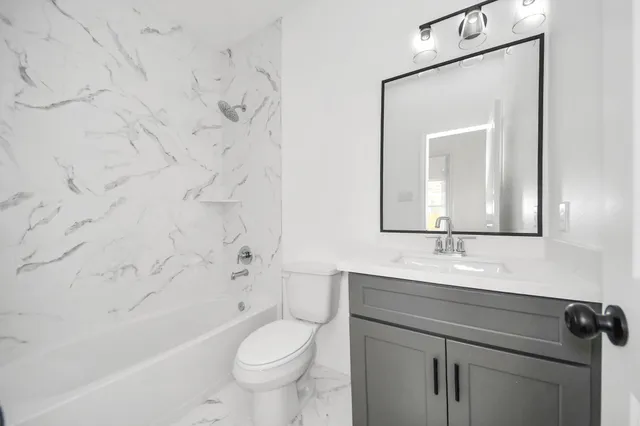 a bathroom with a granite countertop sink a toilet mirror and bathtub