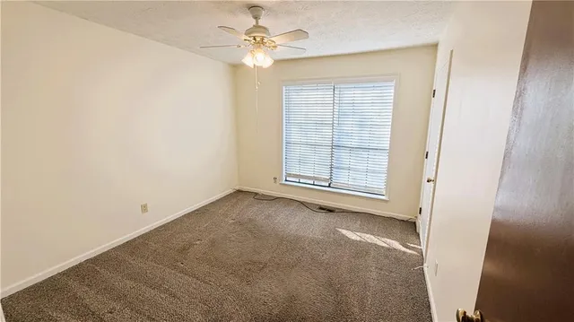 an empty room with windows and fan