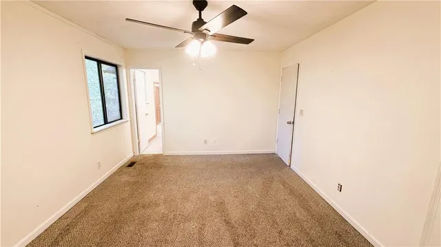 an empty room with a ceiling fan and a window
