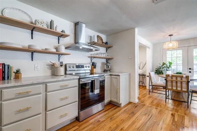 a kitchen with stainless steel appliances granite countertop a lot of cabinets and wooden floor