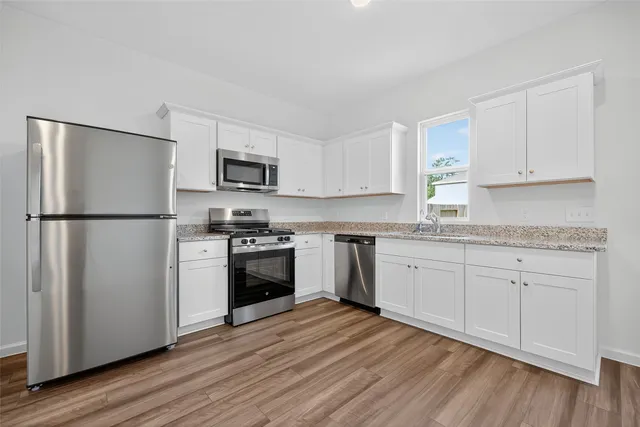 a kitchen with granite countertop a refrigerator stove and wooden floor
