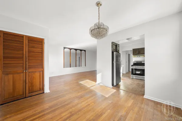 a view of a hallway with wooden floor and a kitchen