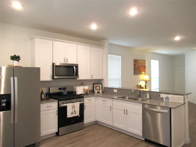 a kitchen with granite countertop white cabinets and stainless steel appliances