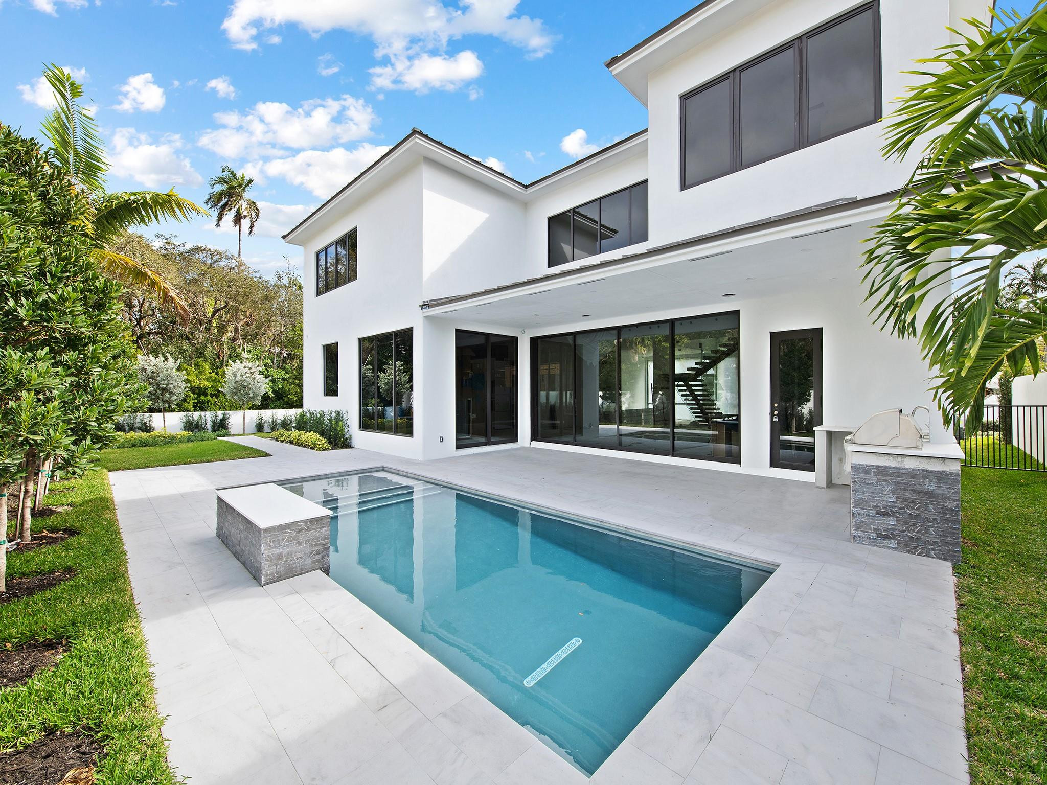 601 Cordova Road Fort Lauderdale, FL 33316 - Photo 2 of 5 a view of a white house with a large pool plants and large tree