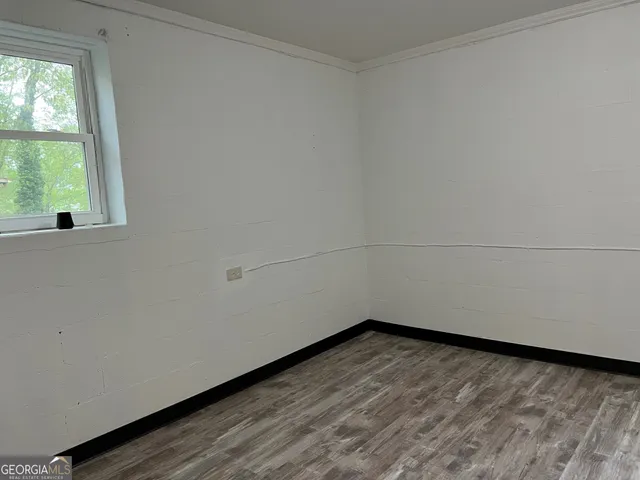 an empty room with wooden floor closet and windows