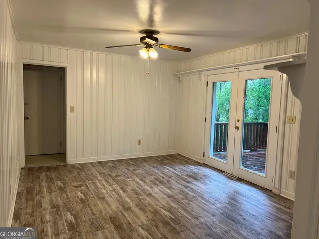 an empty room with wooden floor fan and windows