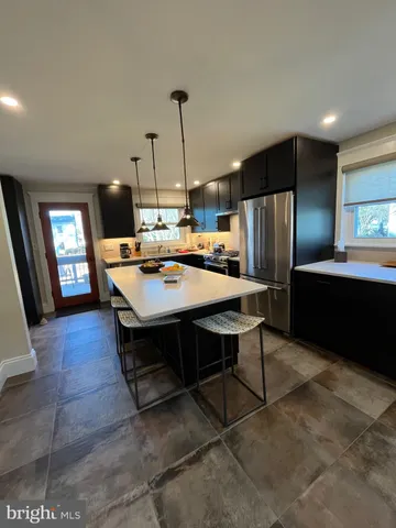 a kitchen with stainless steel appliances kitchen island granite countertop a refrigerator a stove and a sink with wooden floor