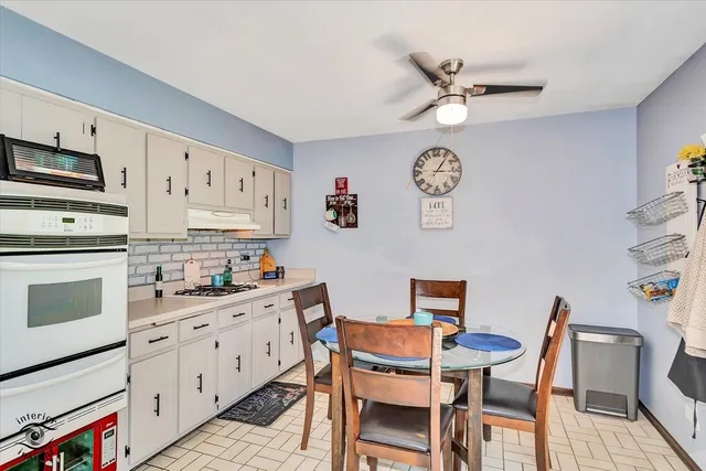 a kitchen with stainless steel appliances a stove a chandelier and a dining table with kitchen view