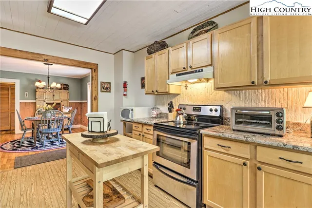 a kitchen with a stove a sink dishwasher and cabinets with wooden floor
