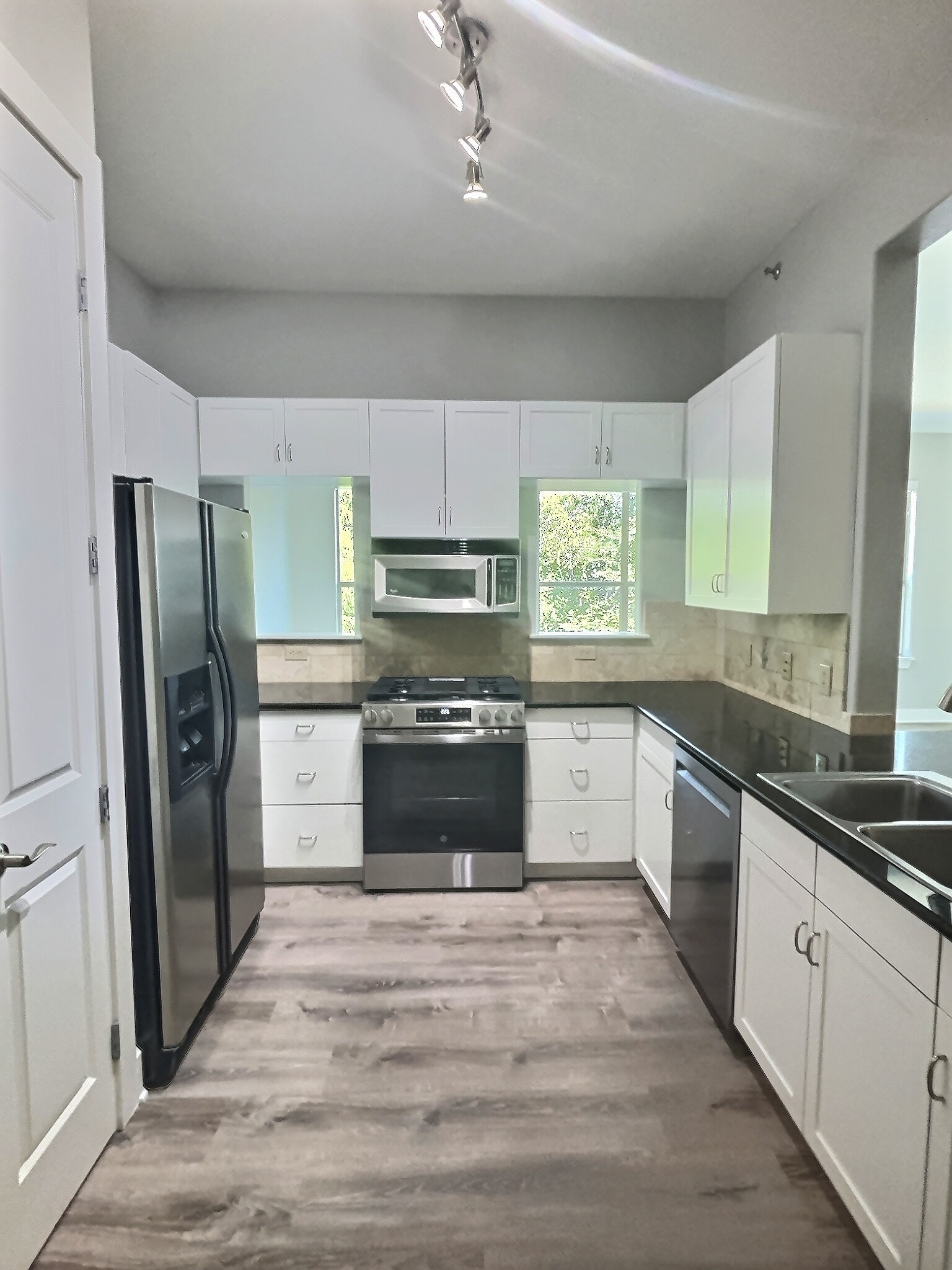 2216 Thornton Road, Unit 421 Austin, TX 78704 - Photo 8 of 31 Kitchen with stainless steel appliances, dark countertops, white cabinets, light wood-type flooring, and rail lighting
