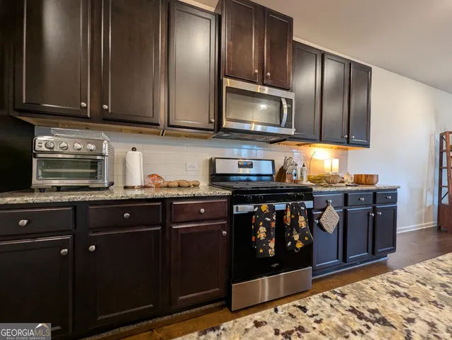 a kitchen with stainless steel appliances granite countertop wooden cabinets a stove top oven and granite counter tops