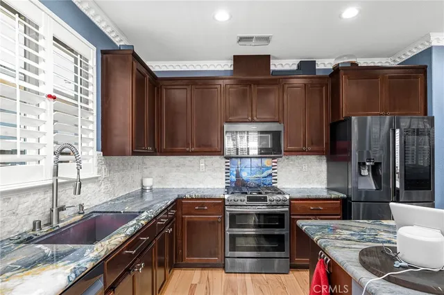 a kitchen with granite countertop a sink appliances and cabinets