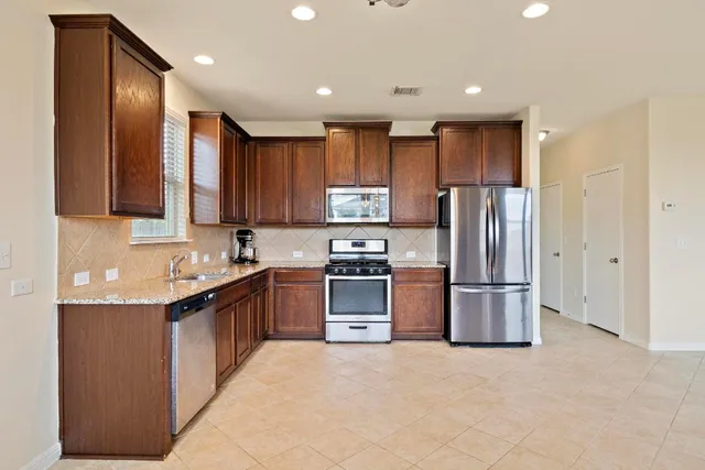 a kitchen with stainless steel appliances granite countertop a refrigerator stove and a sink