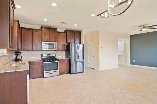 a kitchen with stainless steel appliances granite countertop a refrigerator a stove top oven a sink and dishwasher