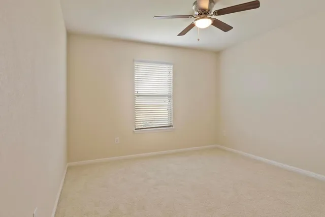 an empty room with a window and a fan