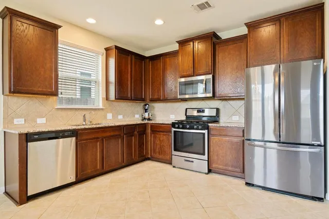 a kitchen with stainless steel appliances granite countertop a refrigerator stove top oven and sink