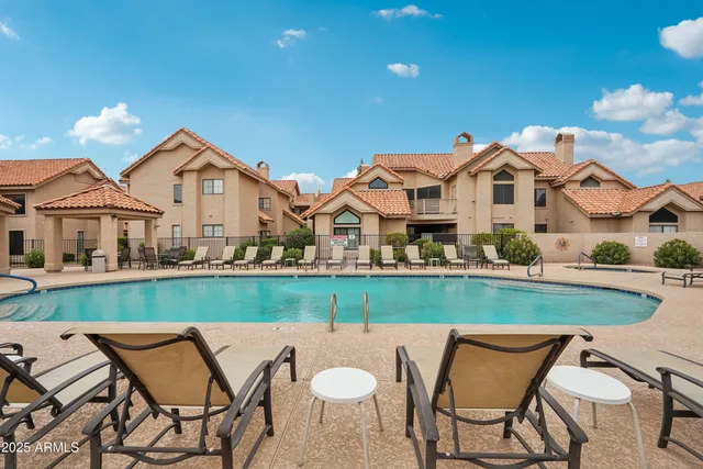 a view of a white house with a table and chairs under an umbrella