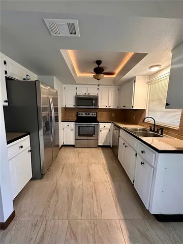 a large kitchen with stainless steel appliances kitchen island granite countertop a stove a sink dishwasher and a refrigerator with wooden floor