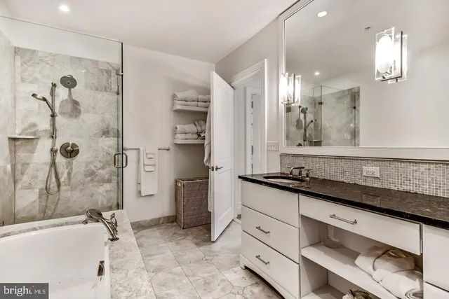 a bathroom with a granite countertop sink a mirror a bathtub and shower