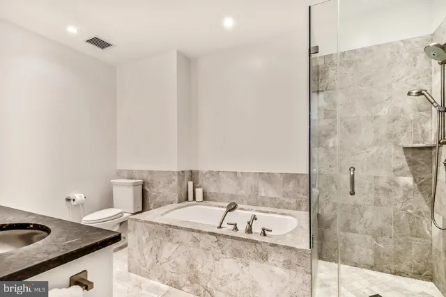 a bathroom with a granite countertop sink and a bathtub