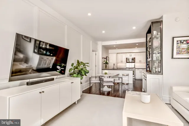 a living room with stainless steel appliances furniture and a flat screen tv