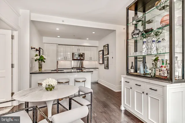 a kitchen with stainless steel appliances granite countertop a table chairs stove and white cabinets