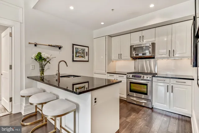 a kitchen with granite countertop a stove a sink and a microwave