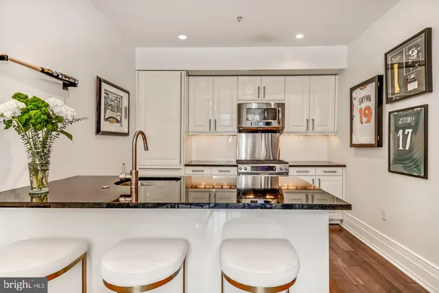 a kitchen with stainless steel appliances granite countertop a white cabinets and couches with wooden floor