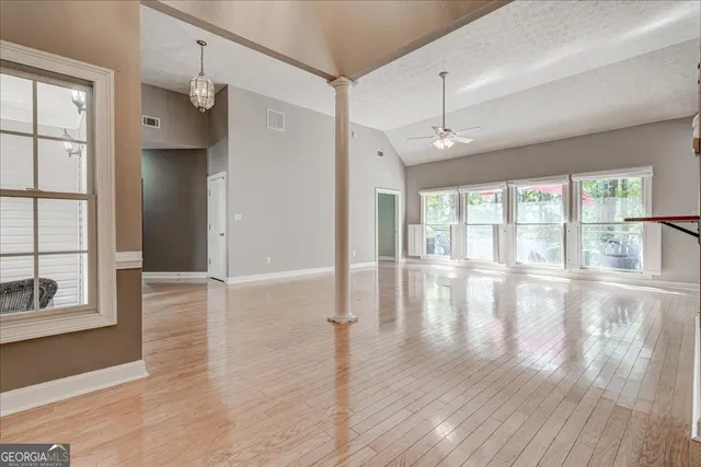an empty room with wooden floor and windows