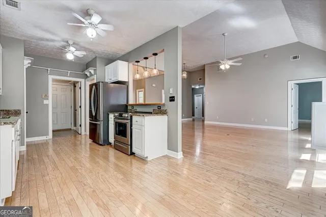 a large kitchen with kitchen island granite countertop a refrigerator and white cabinets
