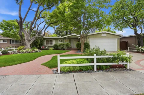 a view of a house with a yard potted plants and a table