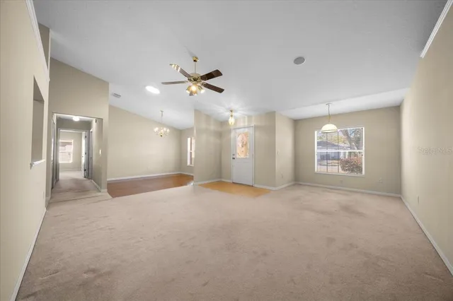 a view of a big room with a chandelier fan and windows
