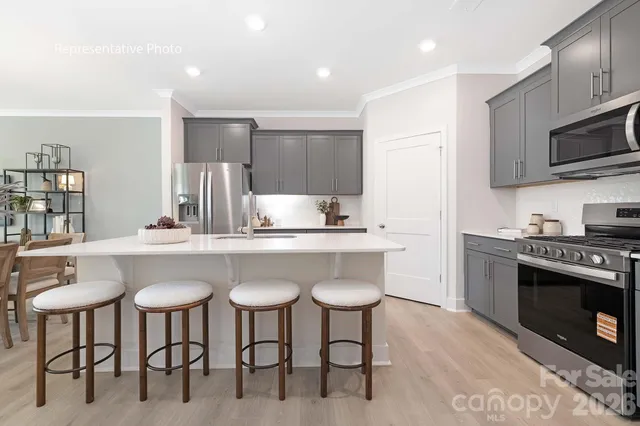 a kitchen with stainless steel appliances a table chairs refrigerator and microwave