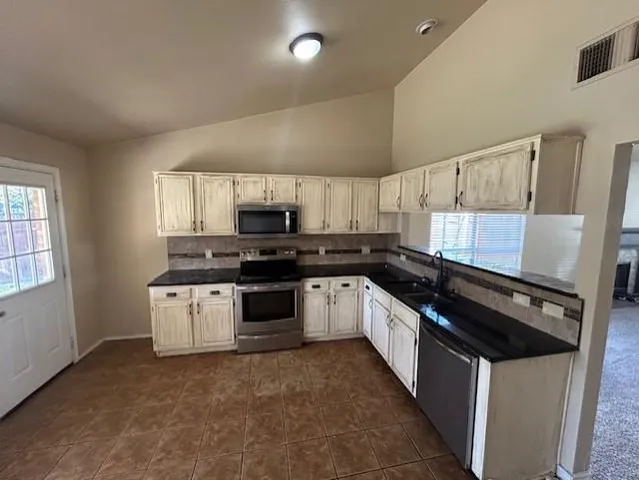 a kitchen with granite countertop a sink a stove and cabinets