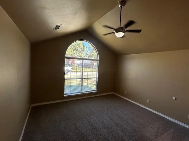 an empty room with a fan & a window