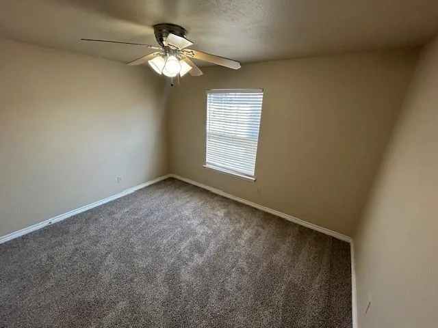 an empty room with a chandelier fan and windows