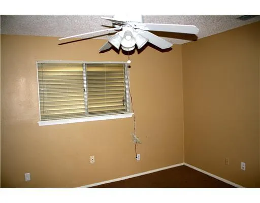 a view of a room with a chandelier fan and wooden floor