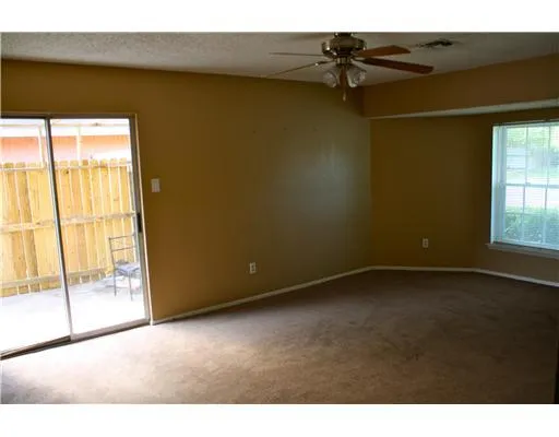 a view of a room with a ceiling fan and window