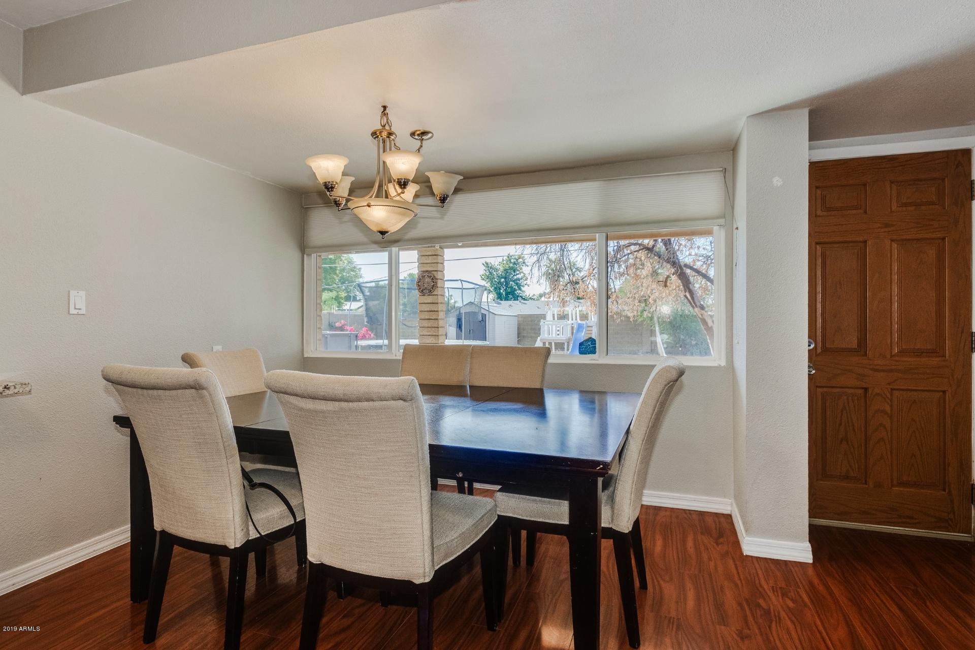 3129 West Cactus Road Phoenix, AZ 85029 - Photo 8 of 19 a view of a dining room with furniture a chandelier and wooden floor